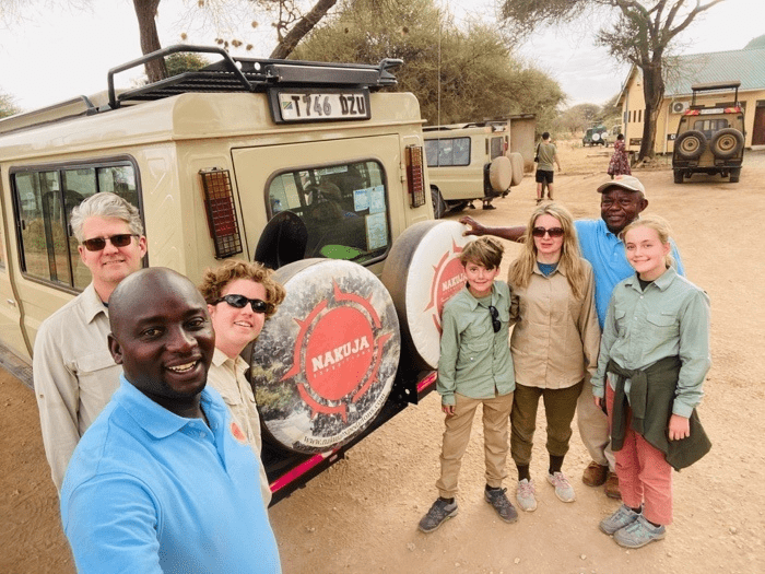 Group of people standing next to a safari jeep